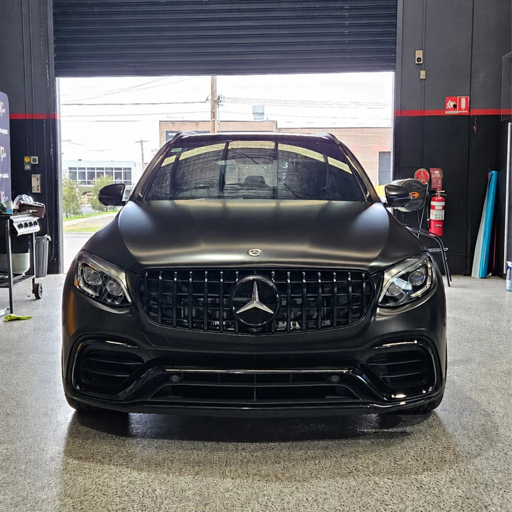 Front view of a Mercedes-AMG SUV featuring a satin black vehicle wrap and gloss black accents inside a detailing workshop