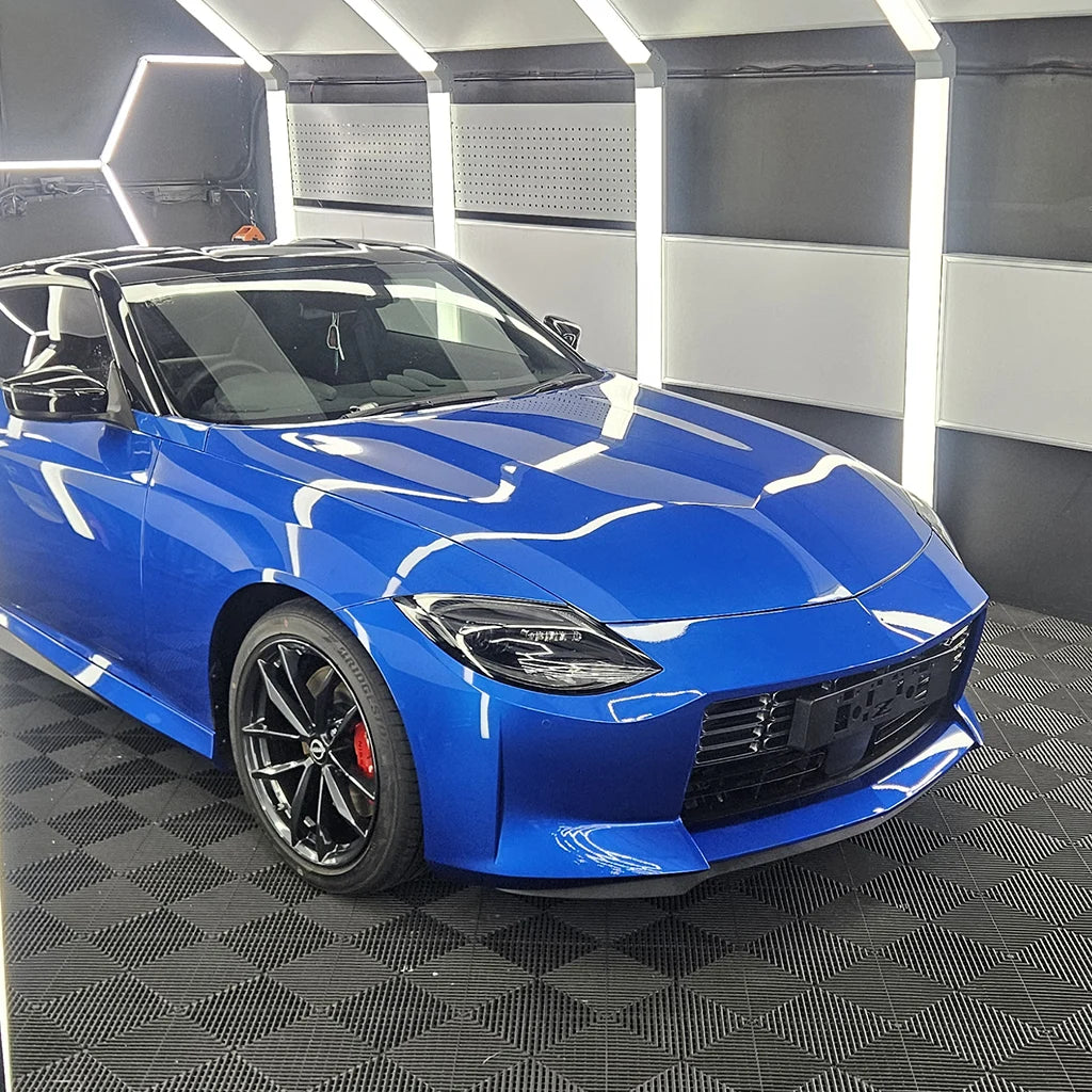 Blue Nissan Z featuring a high-gloss vehicle wrap, black roof and black wheels inside a detailing studio